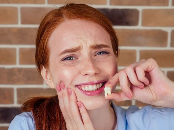 Girl hold a tooth while make a reaction that she had pain in her teeth
